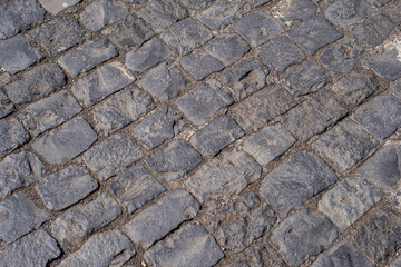 Texture of a roadway of black stone pavers, more than five hundred years old, worn very old from an...