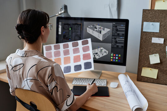Female designer holding color swatches while working with computer at workplace