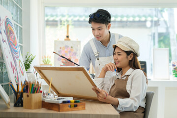 Obraz premium Male and female artist painting on canvas, working for creative project in bright art workshop.