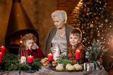 Senior old woman grandmother with grandchildren having festive common dinner in Christmas winter...