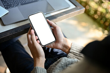 A male freelancer using his smartphone at his desk. phone white screen mockup.