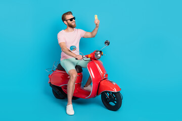 Obraz na płótnie Canvas Full size photo of handsome young man scooter influencer selfie video call gadget wear trendy pink outfit isolated on cyan color background