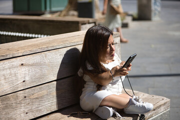 Disabled woman with reduced mobility and small stature sitting on a wooden bench, consulting social...