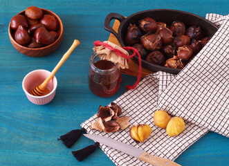 Roasted edible chestnut with honey on blue wooden background. High angle of view, no people.