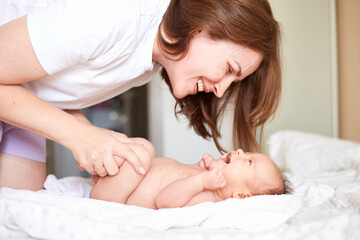 Obraz na płótnie Canvas Mother Massaging Her newborn baby boy. Realistic home portrait