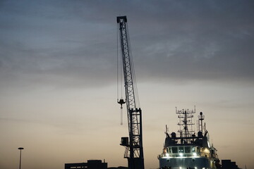 Foto delle gru del porto di Catania al tramonto, il cui cielo crepuscolare evidenzia la loro...