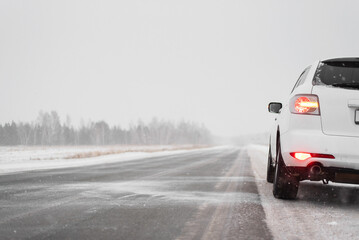 Fototapeta na wymiar Car travel concept. Car on the empty snowy road background.