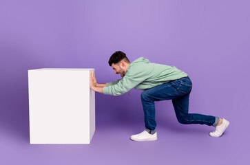 Full length photo of nice young man pushing away white cube platform wear trendy gray clothes isolated on violet color background - obrazy, fototapety, plakaty