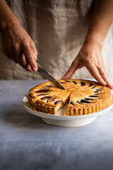 Female slicing a plum pie on a cake stand