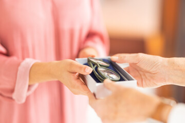 Optometry, eyewear and woman with glasses in a box after shopping in a retail optical store. Closeup of an optometrist helping a patient with her new spectacles in a case at an optics shop or clinic.