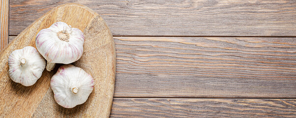 Garlic bulbs on a wooden chopping board. Copy space.