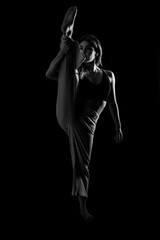 Fototapeta na wymiar Young dancer in studio photo session with a black background, ballet, raising her leg