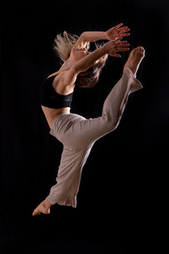 Young dancer in studio photo session with a black background, ballet, performing a jump