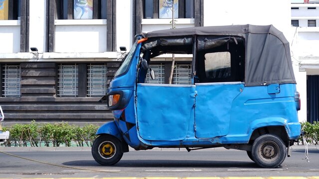 Jakarta three wheeler know as bemo or bajai is parked on the side of the road