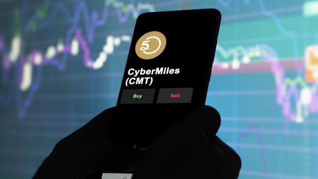 November 3th 2022, Berlin. An investor's analyzing the CyberMiles token 'CMT' coin on screen. A phone shows the crypto's prices to invest