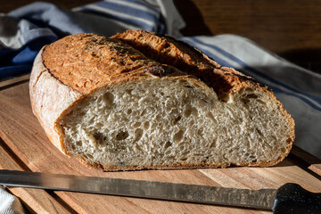 Close-up of a sliced loaf of olive bread placed on a chopping board. Selective focus.