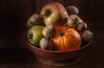 Nuts, oranges and apples in a bowl