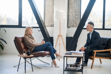 Elegant man in a suit talking to a blonde woman in the office