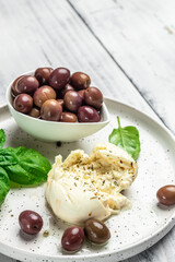 Creamy Italian Burrata Cheese with basil and olive oil on white plate. Italian Mediterranean cuisine. vertical image. top view. place for text