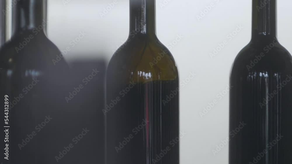 Poster macro shot of red wine filled up in bottles by automated machine in winery