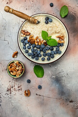 oatmeal porridge with ripe blueberries for healthy breakfast on rustic wooden board. close up Detox and healthy superfoods bowl concept