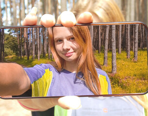 A girl takes a selfie in the forest. View from the phone