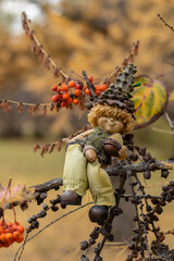 A little gnome, dwarf sits on the tree branch in an autumn park. Autumn gnome in the park