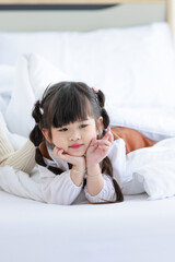 Millennial Asian young beautiful mother in sweater waking up laying down smiling together under thick warm blanket on bed in morning with little cute preschooler daughter girl in bedroom at home