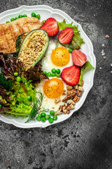 Healthy nutritious paleo keto breakfast diet Fried eggs, avocado, grilled chicken fillet, nuts, strawberries and fresh salad. Keto breakfast or lunch. top view
