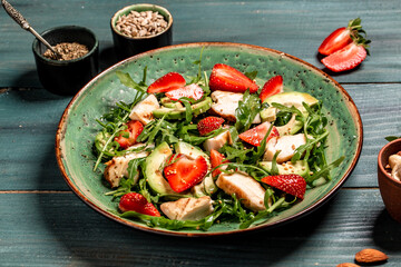 Chicken salad with arugula avocado and strawberries. Plate with a keto diet food. Top view