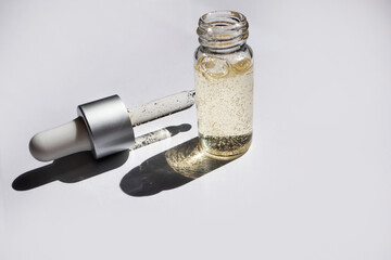 Essential oil in a bottle and pipette on a gray background. Skin care concept. Side view, space for text.