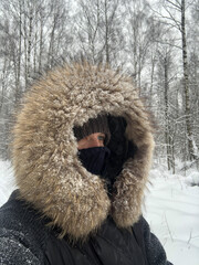 person in warm hood with fur border dusted with snow winter outfit
