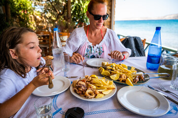 Family eating traditional Greek food in restaurant tavern in Greece.