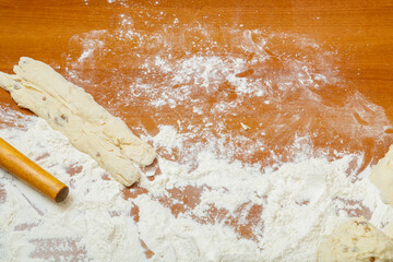 Blanks for braided bread on the table among the flour and rolling pin.
