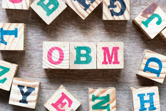 Alphabet letter block in word OBM (Abbreviation of Original brand manufacturer) and another letter on wood background