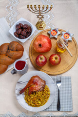 Honey, challah apples pomegranates and dates wine and candles on the table in Rosh Hashanah and spelt with duck leg.