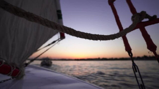 sail boat cruising the Nilo river in the desert during colourful sunrise 