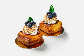 Small square cheesecakes on shortcrust pastry with meringue and blueberries on white