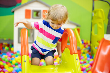 Little boy riding on slide at indoor play center