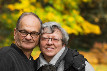 Happy senior couple tourists walking in Warsaw autumn city park. Smiling elderly married in glasses traveling in Europe.