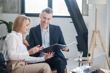 A man and a woman working together in the office and looking involved