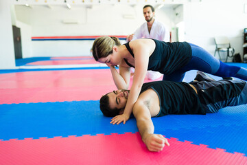 Beautiful woman fighting an attacker at martial arts school