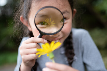 黄色い花を虫眼鏡で見る子供