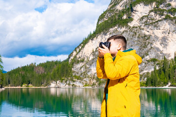 Fototapeta na wymiar Young man photographer holding a camera and taking photos of the Alps. 
