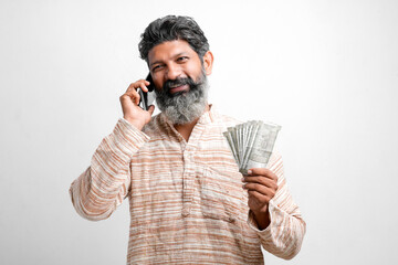 Young indian farmer talking on smartphone and showing money on white background.