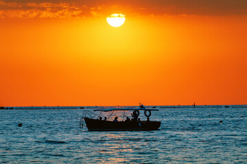 Silhouette of a boat and passengers of tourists at sunset on the sea horizon in Sevastopol, Crimea.Сoncept of evening sea walks, vacation at sea.