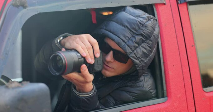 Private detective in glasses taking pictures from car window 4k movie slow motion 