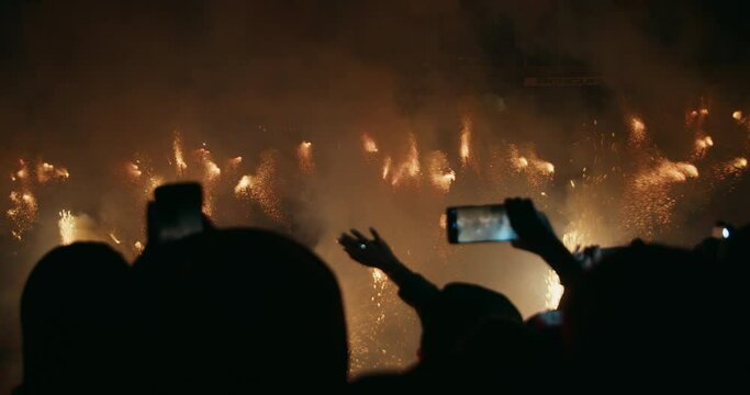 Multiple unrecognizable people on festival event using mobile phones fireworks