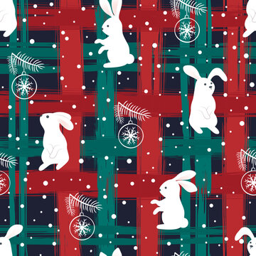 White rabbits with Christmas balls on the background of a checkered pattern in red and green cells. Abstract Christmas pattern of brush strokes. Suitable for wrapping paper and textiles.