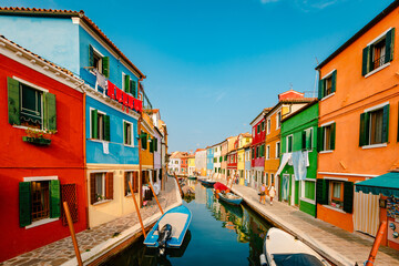 Canal with boats and characteristic colorful houses of Burano with tourists